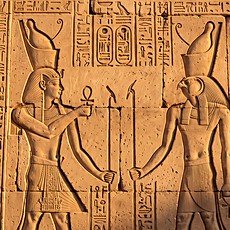 Temple relief showing the pharaoh making an offering before the falcon-headed god Horus.
