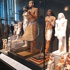Old Kingdom wooden and limestone statues on display at the Grand Egyptian Museum, Giza.